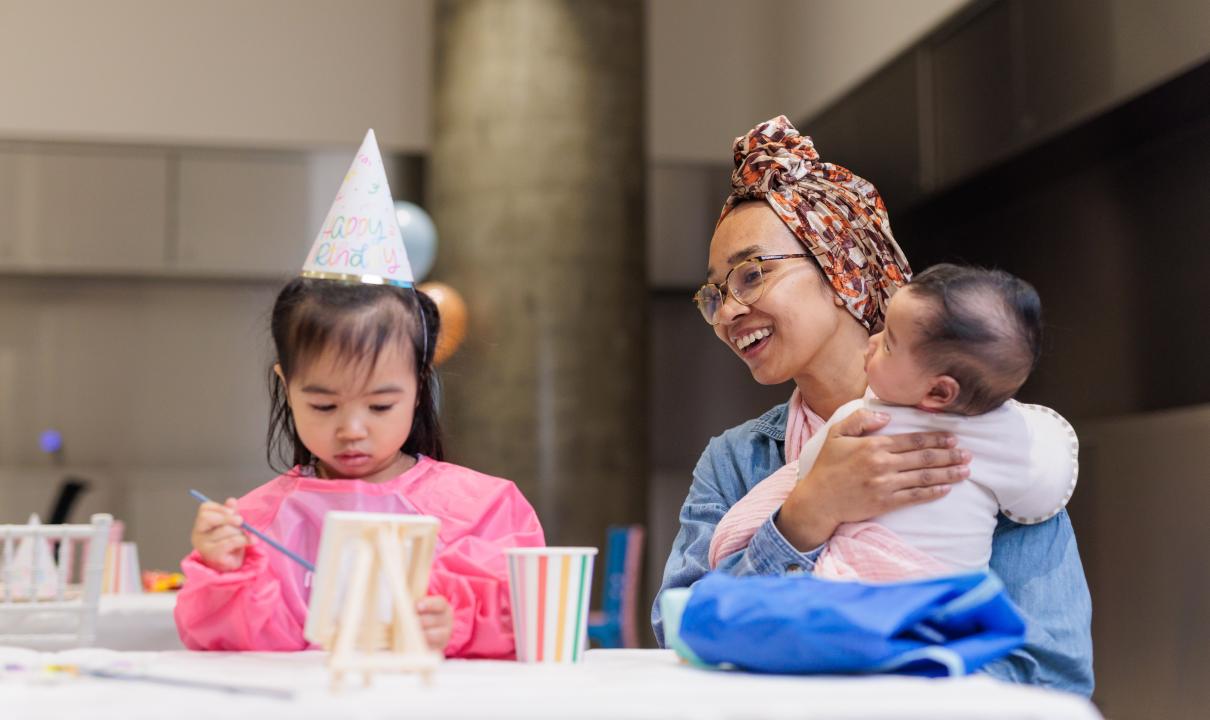 Kid working on craft and parent smiling