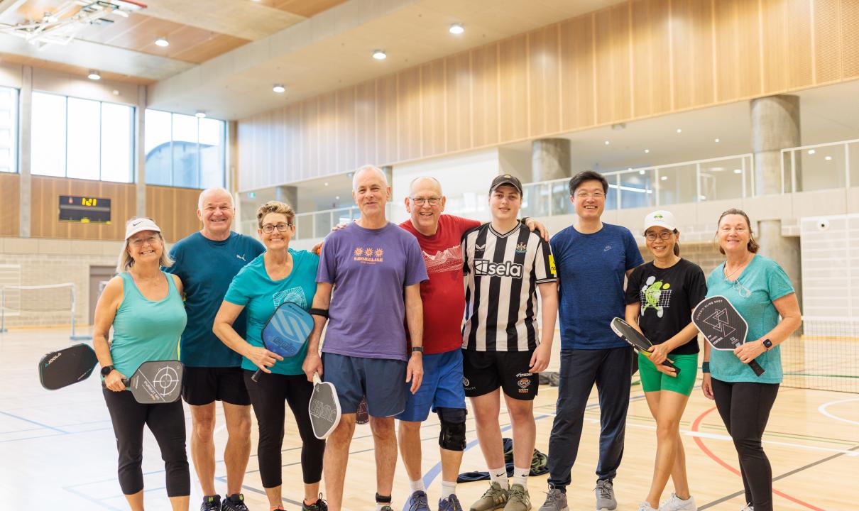 Group of people smiling at indoor sports court