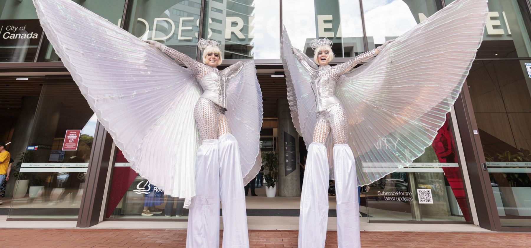Stiltwalkers in glittery costume in front of Rhodes Recreation Centre